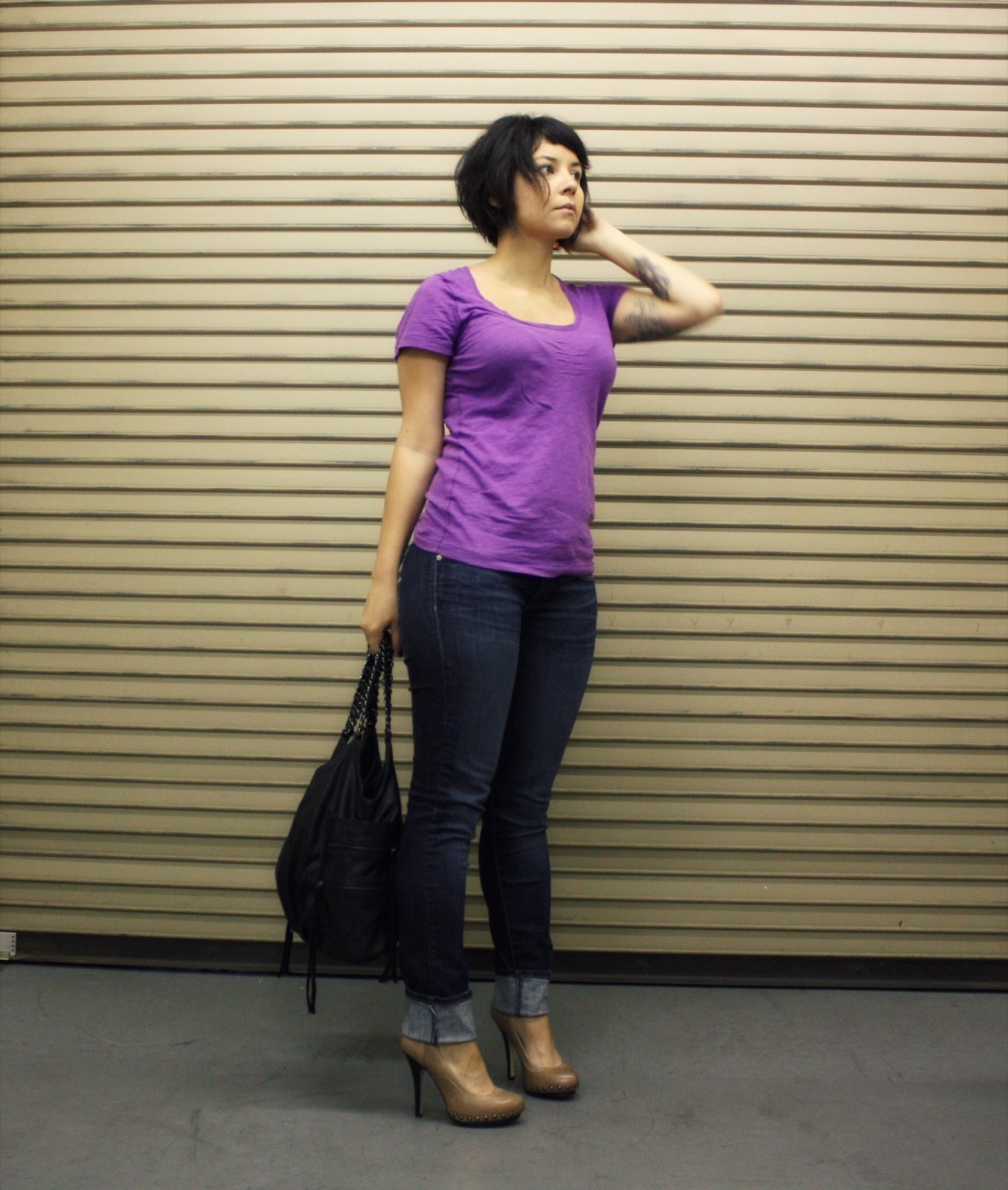 Young woman wearing dark cuffed skinny jeans with a purple tee and platform heels in 2010