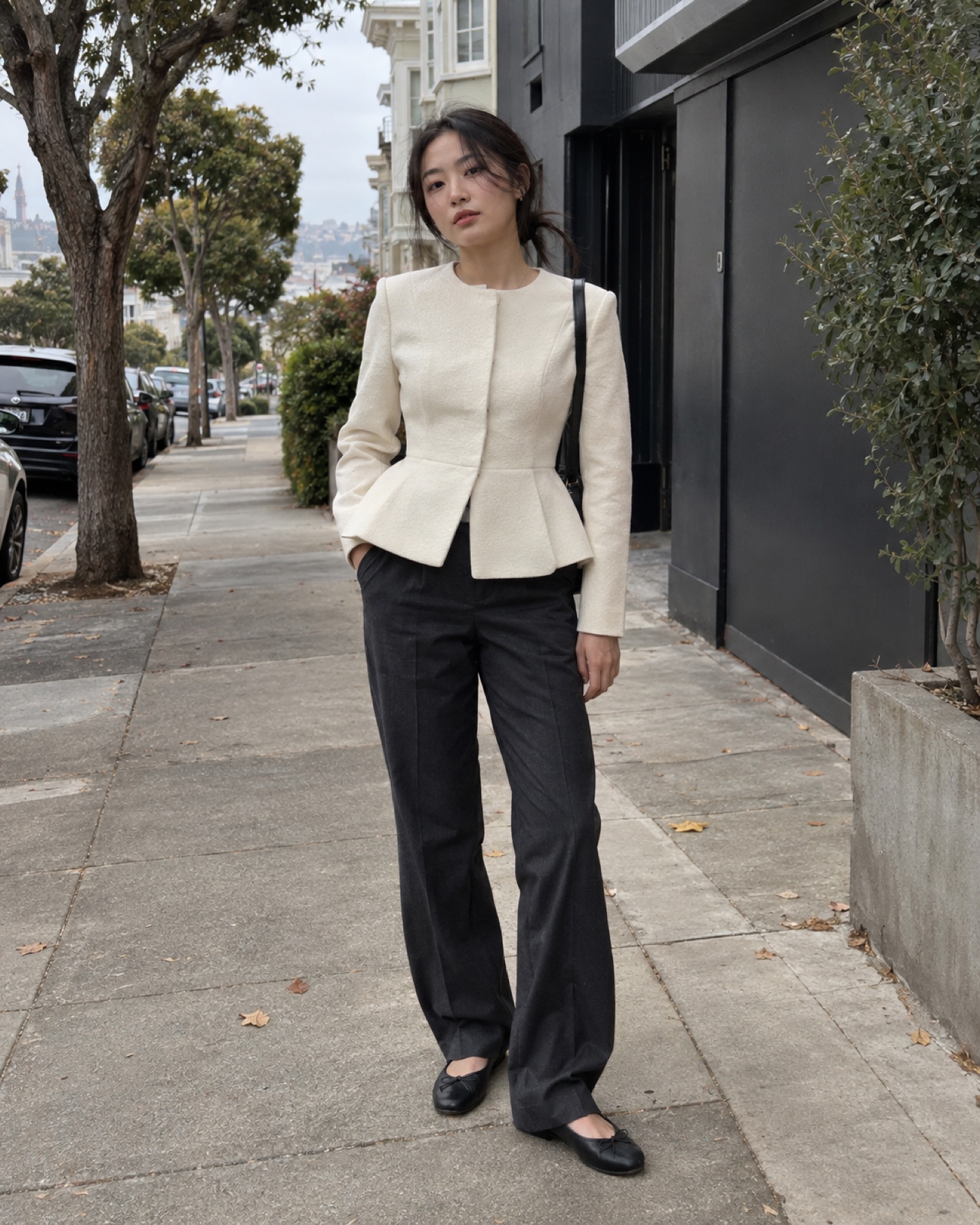 Young woman in 2026 wearing a sculptural ivory peplum jacket with dark trousers and black flats