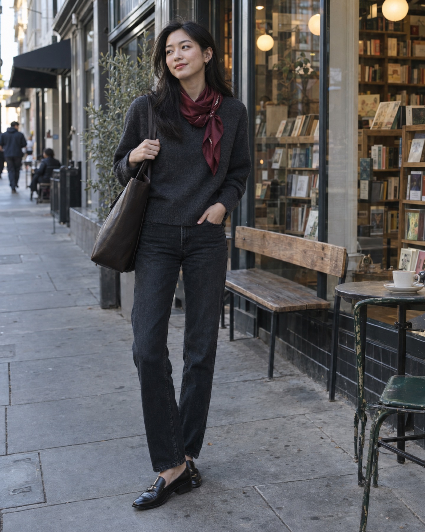 Young woman in 2026 wearing an oxblood silk statement scarf with a charcoal sweater and dark jeans